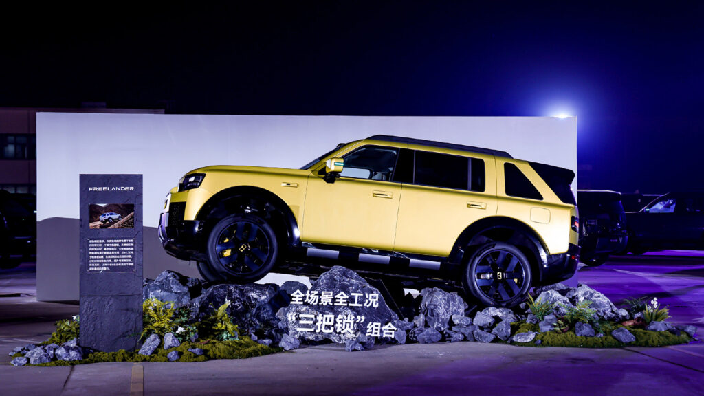 Yellow Freelander 8 SUV displayed on a rocky off-road installation at a launch event.