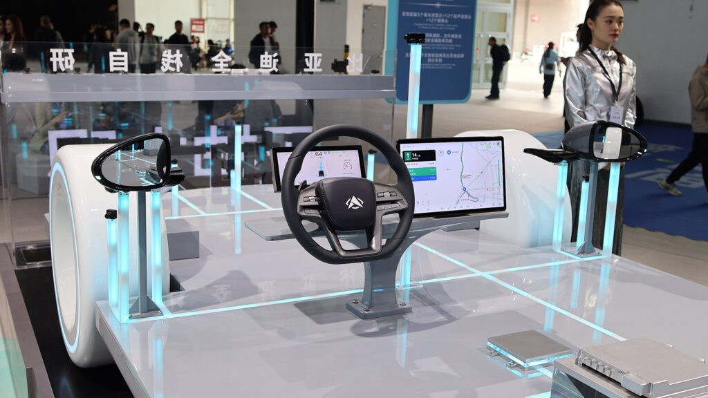 BYD assisted-driving demonstration featuring a steering wheel, digital instrument cluster, navigation screen and side mirrors at the 2026 Beijing auto show.