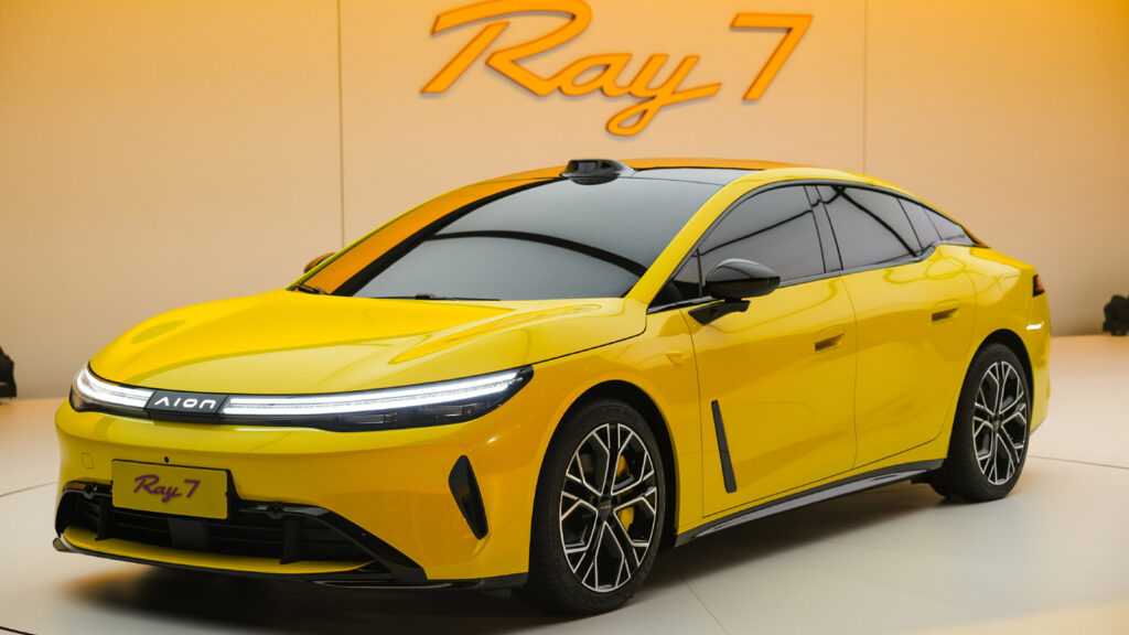 A yellow GAC Aion Ray 7 electric sedan shown from the front three-quarter view, featuring the brand’s new illuminated Aion logo.