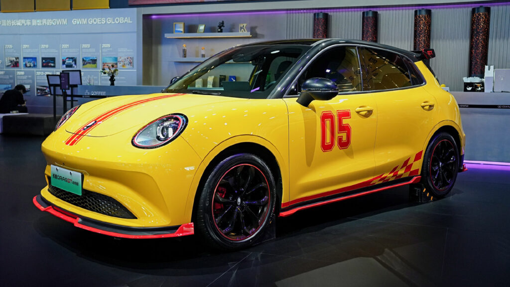 A yellow GWM Ora 5 GT with red racing stripes, black wheels and a large rear wing on display.