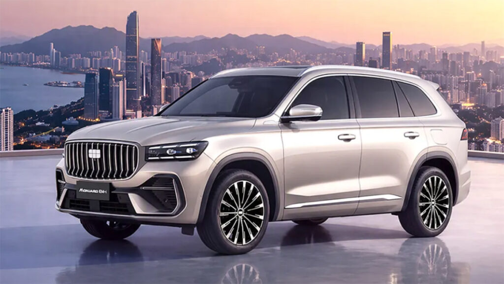 Silver Geely Monjaro EM-i hybrid SUV shown from a front three-quarter angle against a waterfront city skyline at sunset.
