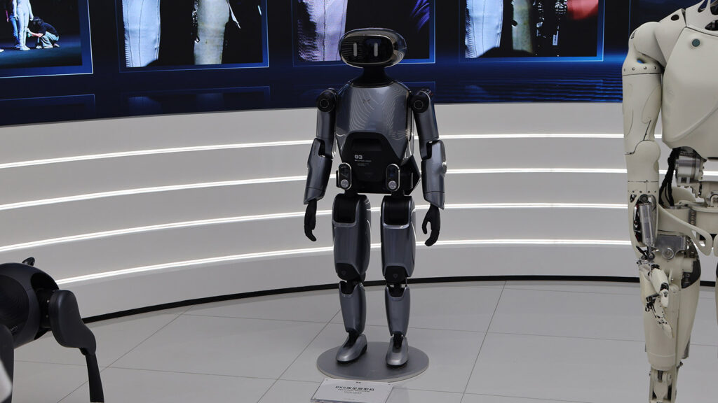 A dark gray Xpeng humanoid robot stands alongside other robots in a display area at the company