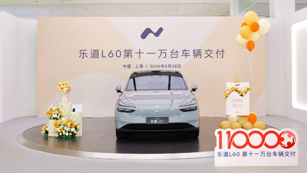 Front view of a gray Onvo L60 beside a 110,000-delivery milestone sign at a ceremony in Shanghai.