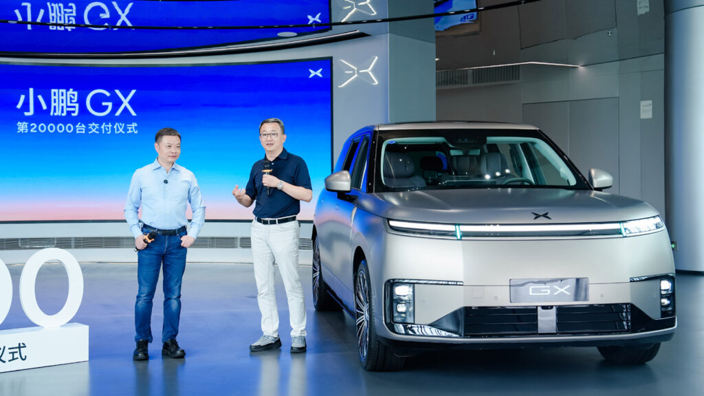 Xpeng chairman and CEO He Xiaopeng and Bosch Huayu Steering Systems general manager Bu Xinwen speak beside a silver Xpeng GX at a ceremony marking 20,000 deliveries of the model.