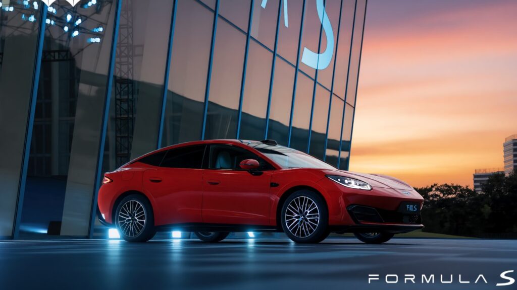 BYD Fang Cheng Bao enters electric sedan market with Formula S launch Red Fang Cheng Bao Formula S electric sedan parked outside a glass-fronted building at sunset.