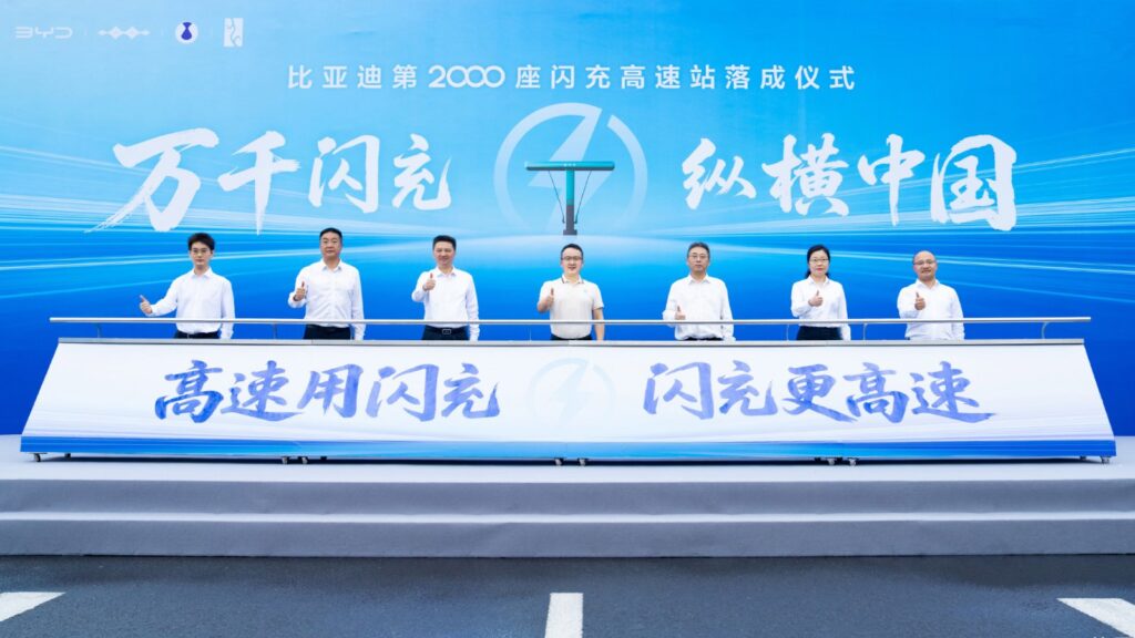 7 participants give thumbs-up gestures onstage at a ceremony marking BYD’s highway flash-charging network reaching 2,000 stations.