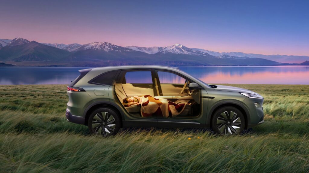 Cutaway promotional image of a green Buick Electra E7 beside a lake, showing a passenger resting on reclined seats.