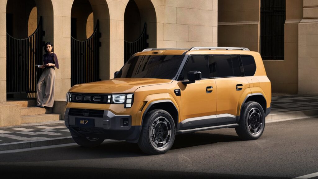 GAC unveils plan to buy auto JV stake from FAW in share deal Gold GAC Trumpchi Yue 7 SUV viewed from the front three-quarter angle, parked beside a building with arched entrances.