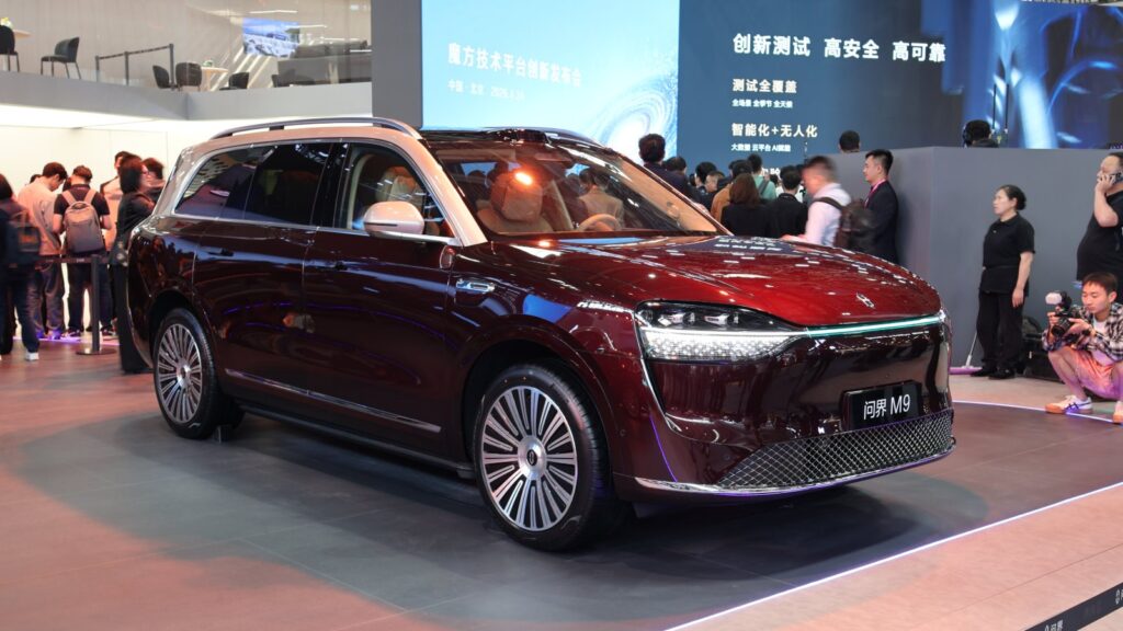 Front three-quarter view of a burgundy Aito M9 SUV with a contrasting light-colored roof at the 2026 Beijing Auto Show.