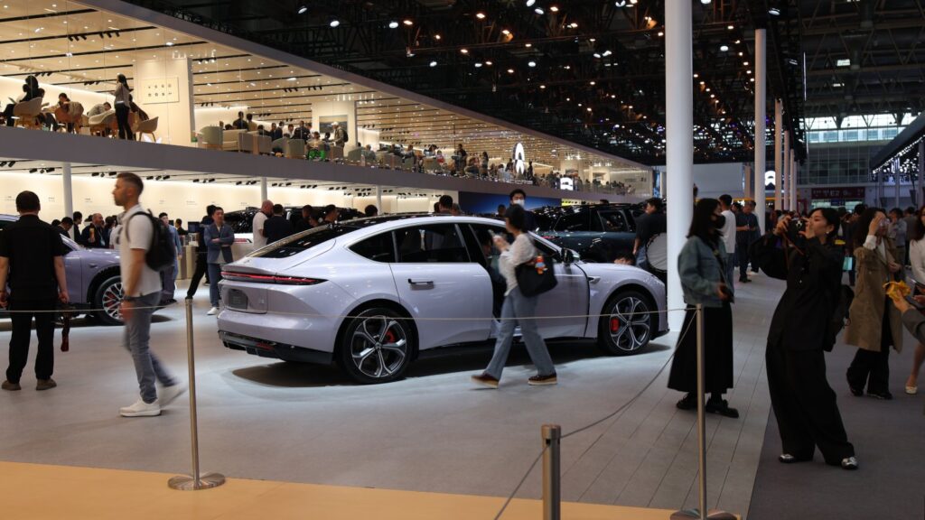 Visitors walk past a light purple Nio sedan at the automaker