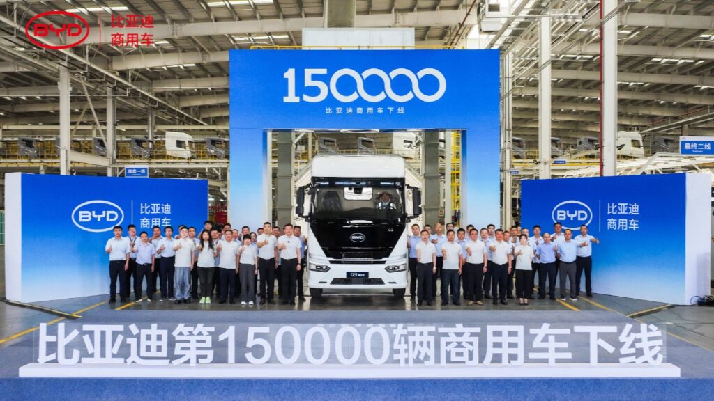 A BYD Q3 electric semi-truck surrounded by staff at a ceremony marking production of 150,000 commercial NEVs at the Huai
