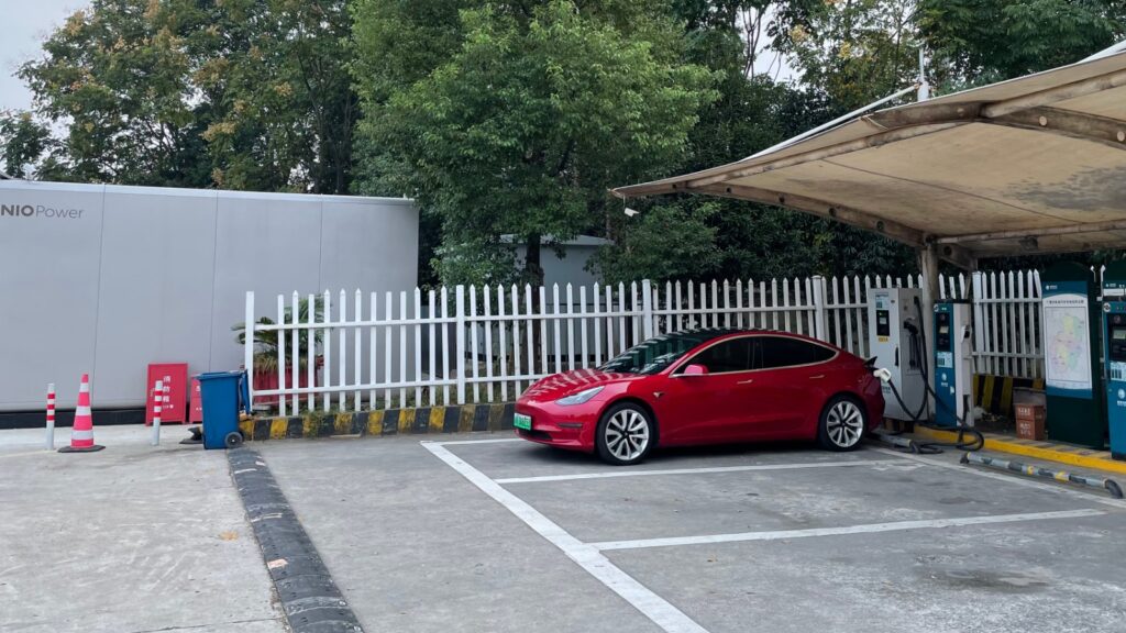 A Tesla Model 3 charging at a highway service area.