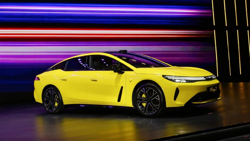 Yellow GAC Aion Ray 7 electric sedan displayed onstage, viewed from the front and side.