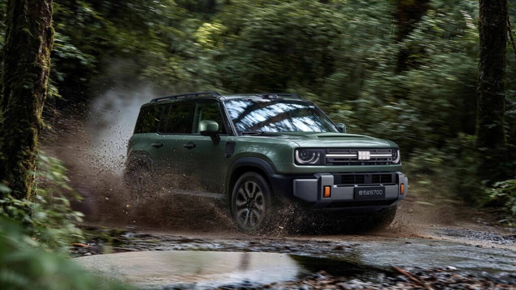 Green Geely Galaxy Cruiser 700 splashing through a muddy forest trail.