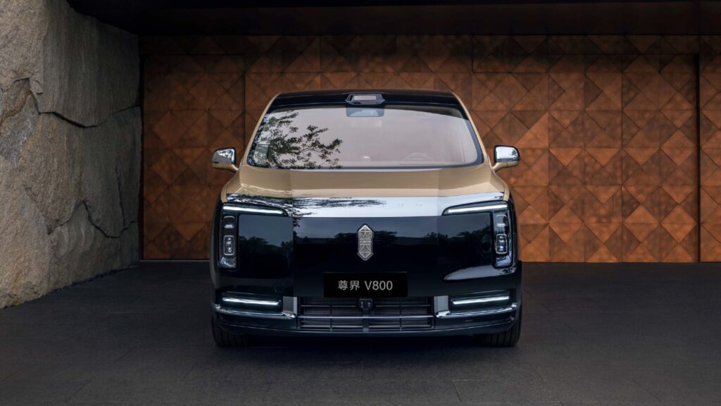Huawei-JAC brand Maextro pledges component redesign after brake test controversy Front view of a gold-and-black Maextro V800 luxury MPV parked in front of a patterned wooden wall.