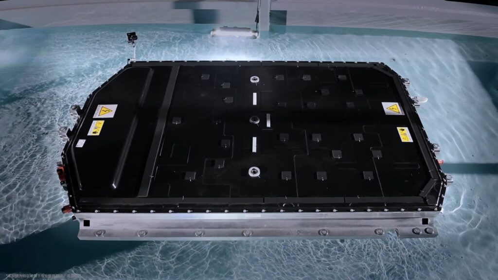 Li Auto launches Lianshan in-house EV tech system, backs self-developed batteries with lifetime safety pledges A black Li Auto battery pack with yellow high-voltage warning labels sits submerged in a pool of clear water during a water immersion test.