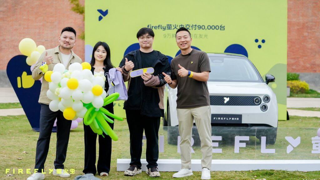 4 people pose with a balloon bouquet in front of a white Firefly EV at the brand