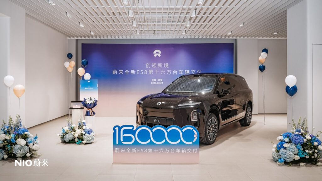 A Nio ES8 displayed with flowers, balloons and a sign marking 160,000 deliveries.