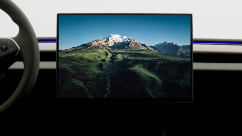 Tesla Model 3 cabin with a 16-inch central touchscreen displaying a mountain landscape.