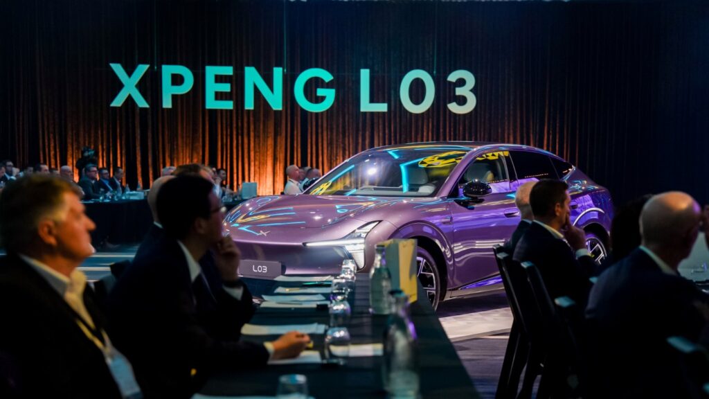 Xpeng steps up Australia, New Zealand push with Mona L03 launch A purple Xpeng L03 SUV displayed among seated guests beneath illuminated XPENG L03 lettering.
